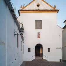 Fachada principal del edificio blanco con puerta arqueada y ventana superior