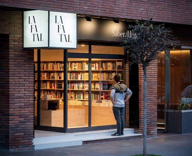 Fachada exterior de La Fatal con iluminación cálida y estanterías visibles