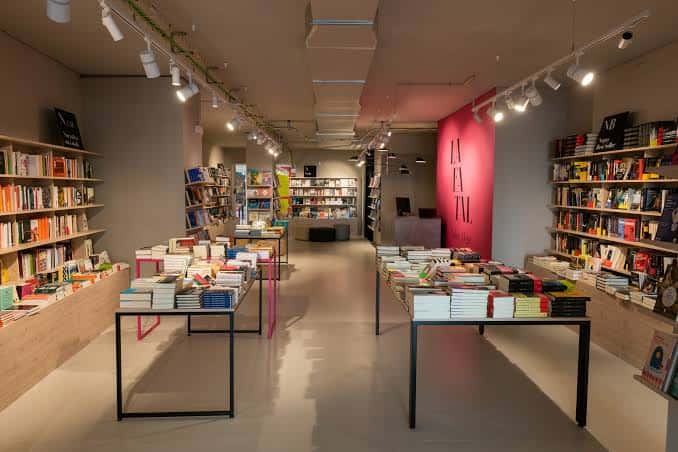 Interior principal de la librería con mesas de libros y pared rosa
