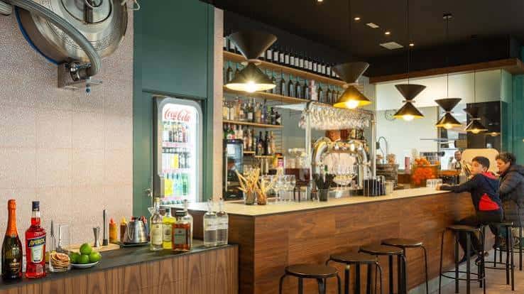 Bar interior de Il Farabutto con estantería de botellas y clientes sentados