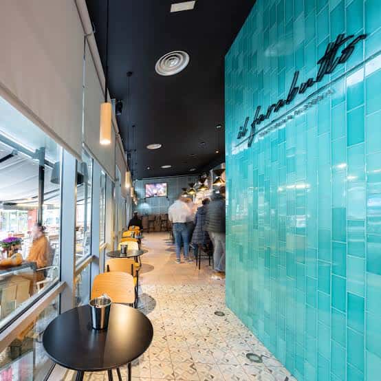 Pasillo interior del restaurante con pared azul turquesa y logo 'il farabutto'