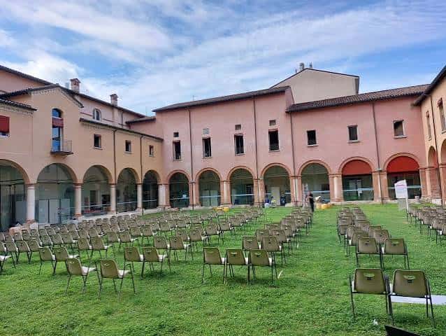 Patio del Chiostro del Carmine preparado para evento con sillas en el césped