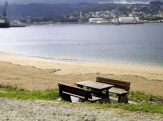 Zona de descanso con mesa y bancos de madera frente al mar