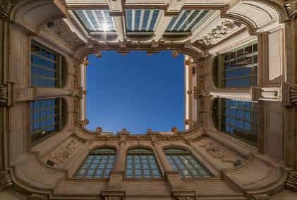Cielo abierto desde el patio central del palacio, mostrando detalles arquitectónicos y ventanas superiores