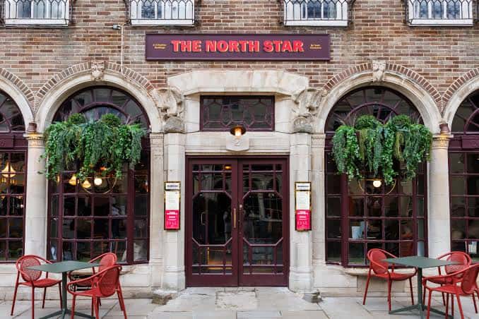 Fachada principal de The North Star con entrada y mesas exteriores