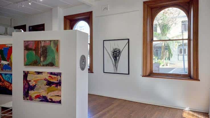 Interior de la galería con obras de arte expuestas y ventanas arqueadas