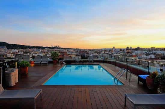 Terraza con piscina infinita y vistas panorámicas de Barcelona al atardecer