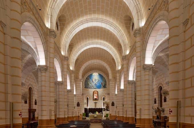 Interior de la iglesia con bóvedas iluminadas y altar central decorado