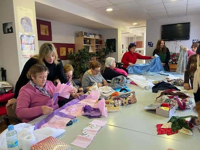 Actividad de manualidades en el interior del centro con participantes mayores trabajando en grupo