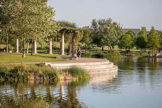 Paseo junto al lago con personas caminando bajo árboles frondosos