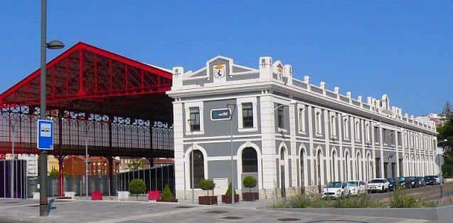 Vista exterior de la Estación del Norte en León con su distintiva estructura metálica roja y fachada neoclásica