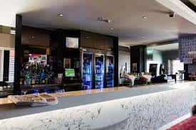Bar interior del hotel con mostrador de mármol, neveras y zona de recepción