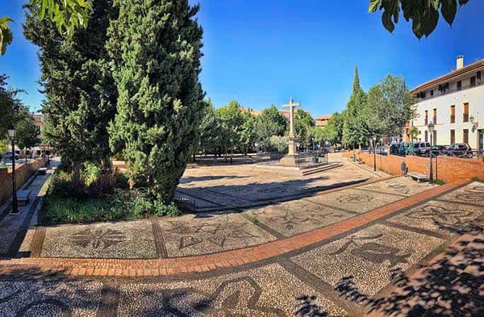 Plaza empedrada con diseño de mosaico y vegetación en el Campo del Príncipe