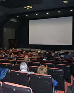 Sala de cine con butacas rojas y pantalla en blanco