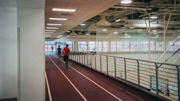 Interior del gimnasio mostrando pista de atletismo y área deportiva con personas
