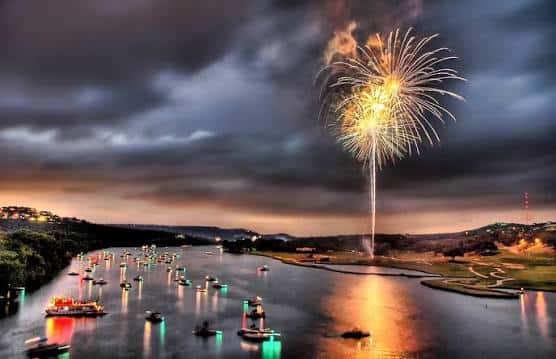 Vista nocturna de fuegos artificiales sobre el Lago Austin con barcos decorados