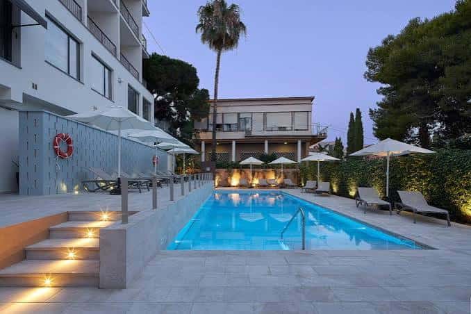 Piscina del hotel con tumbonas y palmeras al atardecer