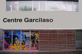 Detalle de la entrada lateral mostrando murales artísticos junto a la fachada de madera