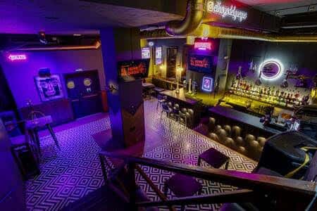 Vista panorámica del interior del bar con iluminación neón y barra principal