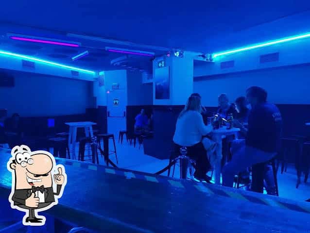 Interior del bar con ambiente nocturno y clientes sentados en mesas