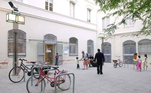 Entrada principal de la biblioteca con personas y bicicletas en el patio