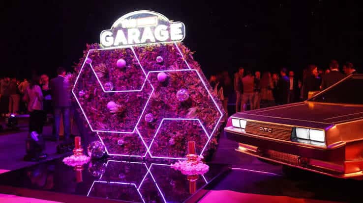 Escenario decorado con neón y pared floral para evento en The Garage