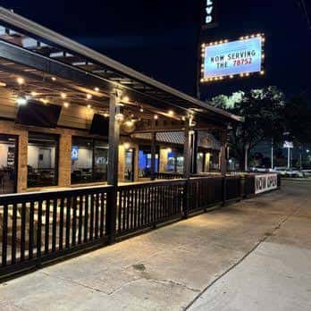 Vista nocturna de la fachada exterior de Boulevard Social con iluminación cálida y letrero luminoso