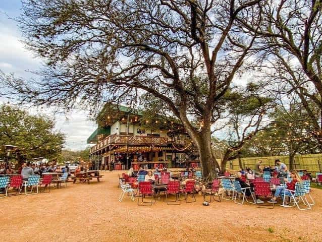 Área de eventos al aire libre rodeada de árboles grandes con decoración festiva