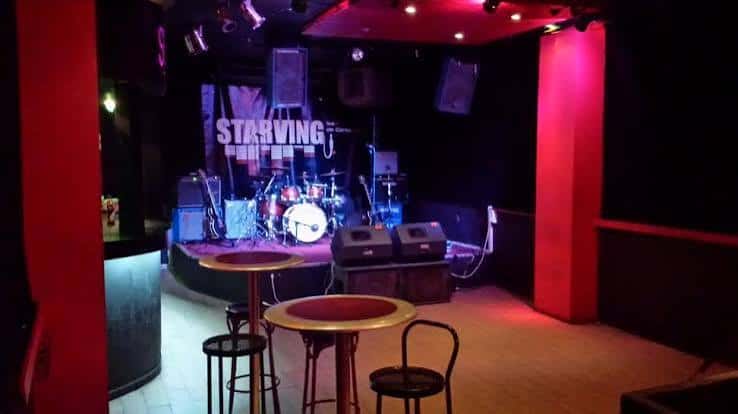 Escenario de la sala con equipo musical y luces rojas