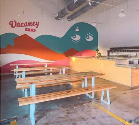 Interior del taproom con murales coloridos y mesas largas