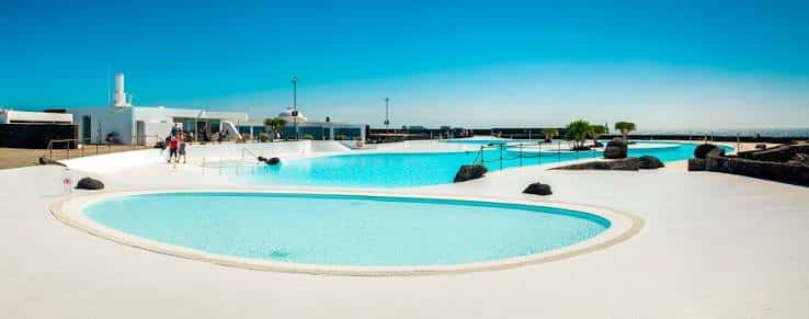 Piscina principal del complejo con personas caminando y arquitectura blanca minimalista