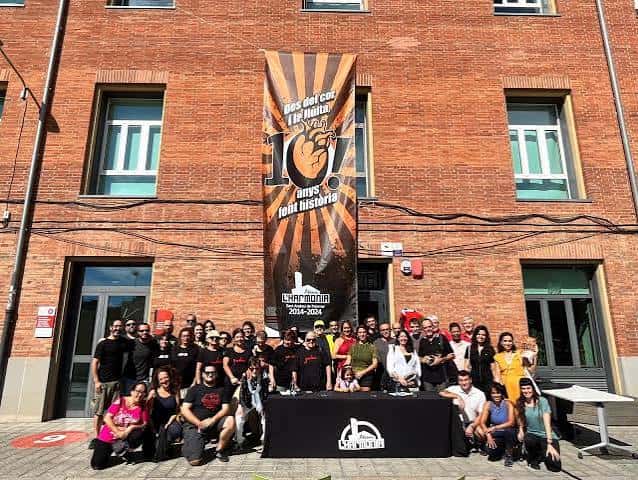 Grupo de personas reunidas frente al Ateneu L'Harmonia con pancarta conmemorativa