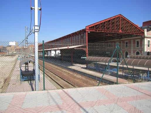 Vista lateral de la estación mostrando el andén con estructura metálica roja y vías