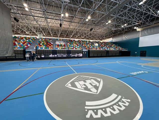 Pista deportiva interior con logo central y gradas multicolor