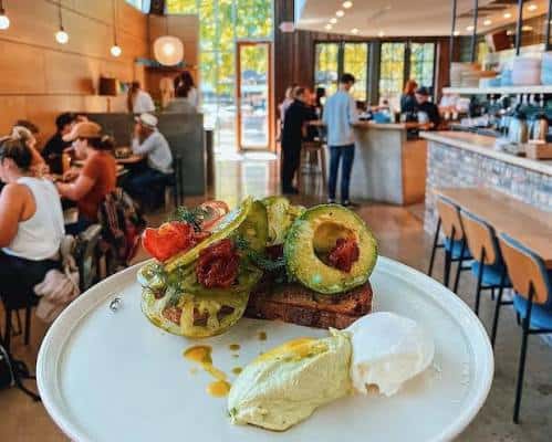 Plato de brunch en el interior del café con clientes al fondo
