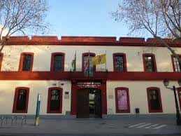 Fachada principal del edificio con banderas institucionales en un día soleado