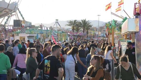 Multitud de visitantes caminando entre casetas y atracciones en el recinto ferial
