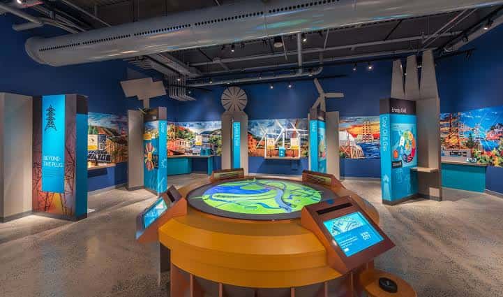 Exhibición interactiva de energía renovable con paneles informativos y mapa táctil central