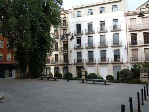 Vista general de la plaza empedrada con bancos, árboles y edificios históricos de Alcoy