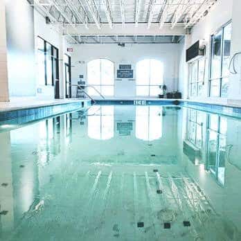 Piscina interior del Castle Hill Fitness con grandes ventanales y techo industrial