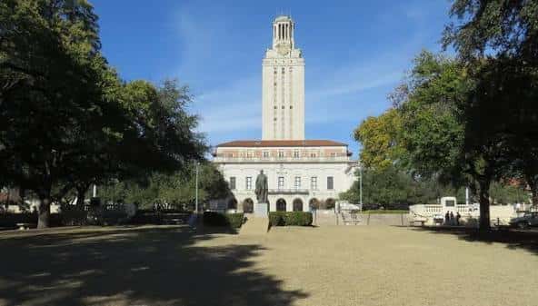 Vista frontal del Edificio Principal de UT Austin con la torre y el césped del Main Mall
