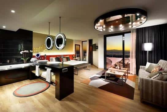 Interior de suite ejecutiva con cama king-size, baño integrado y vistas al atardecer desde el balcón
