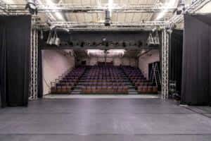 Interior del auditorio con escenario, iluminación profesional y butacas en gradas