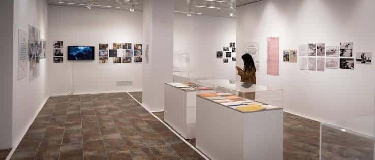 Vista general de la sala de exposiciones con vitrinas y obras en pared