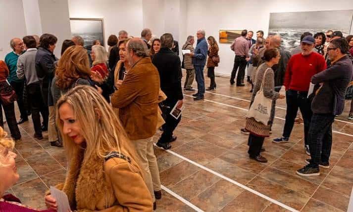 Evento social en la sala con asistentes conversando durante una inauguración