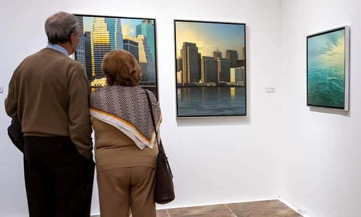 Pareja observando fotografías urbanas expuestas en la sala blanca