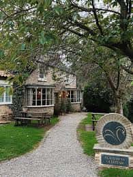 Vista exterior del The Black Swan at Oldstead con su letrero distintivo y sendero de grava