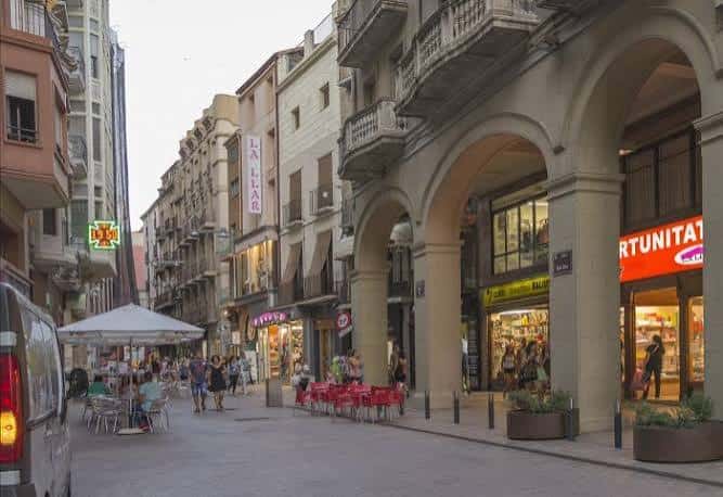 Vista de la calle comercial con arcos y tiendas iluminadas