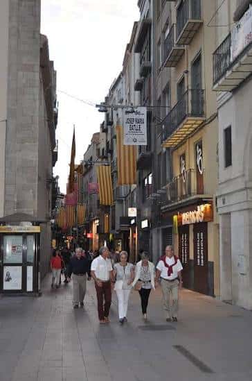 Calle peatonal decorada con banderas catalanas y personas caminando