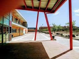 Entrada principal del edificio con estructura roja y pasillo cubierto